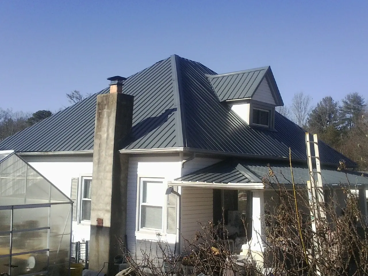Dark blue standing seam metal roof on a white farmhouse with dormer — Slate & Tile Roof Repair by Roofing Brothers in Leonardville