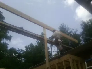 Carpenter setting a ridge beam over a new addition frame — Ice Dam Removal by Roofing Brothers in Leonardville