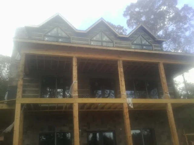Dormers and porch framing on a large log home under construction — Roof Coating work by our crew in Leonardville