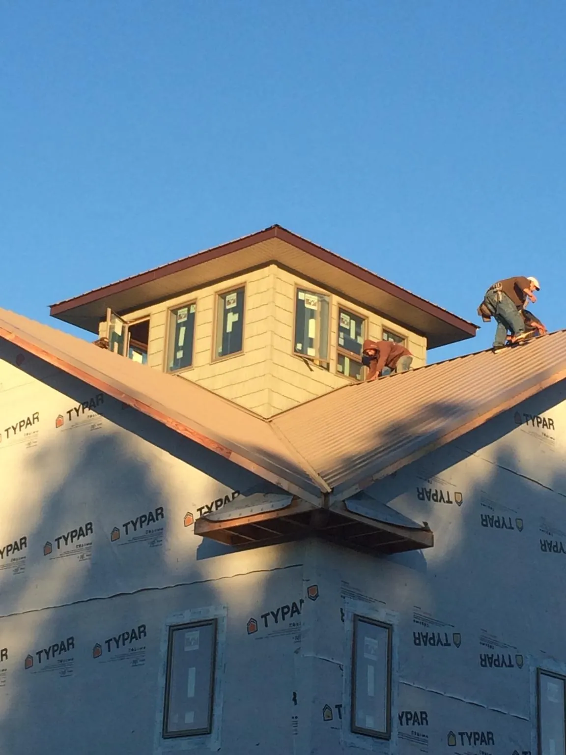 Roofers working around a rooftop cupola on a new metal roof at sunset — Roof Waterproofing in Leonardville by Roofing Brothers